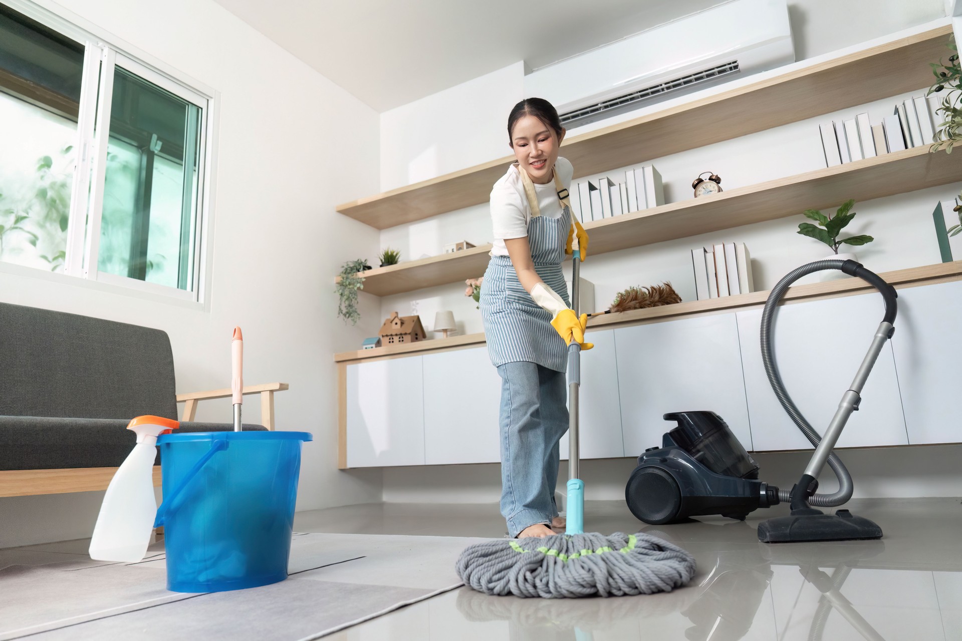 Home Cleaning. Woman mopping floor in modern living room with eco-friendly products.